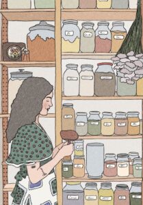 A woman is standing in her pantry. She has long, dark hair and is wearling a green top. There are shelves behind her filled with jars of dry goods.
